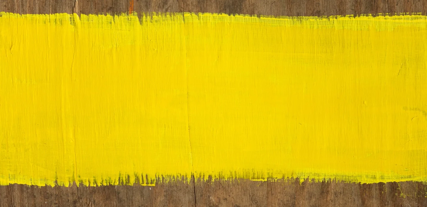 Decorative background of a piece of wood with yellow paint